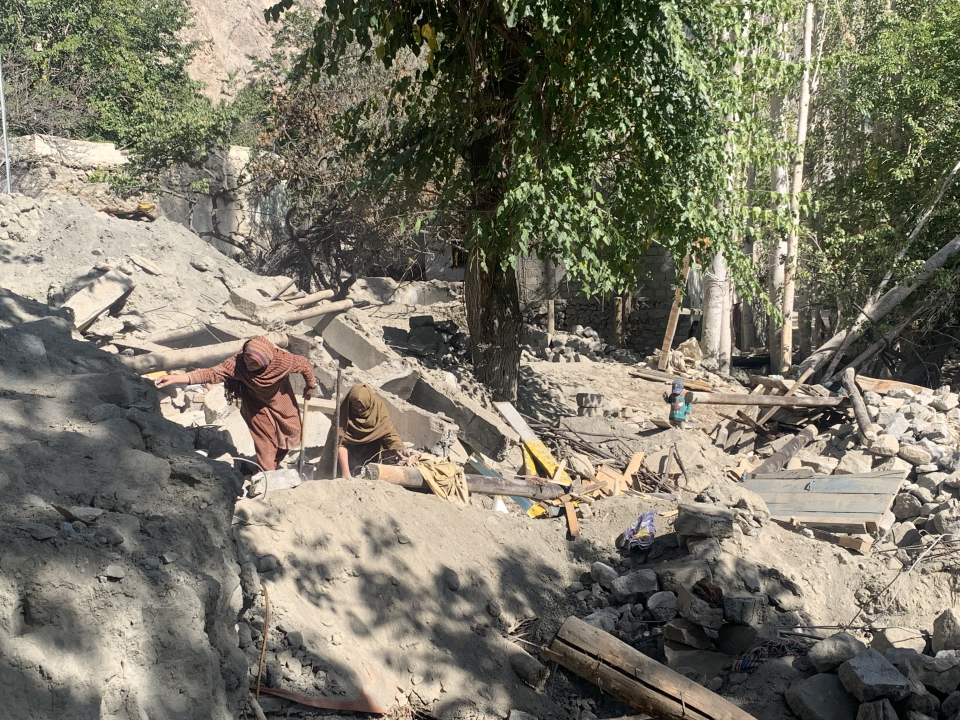 Pakistani women look for lost items among rocks.