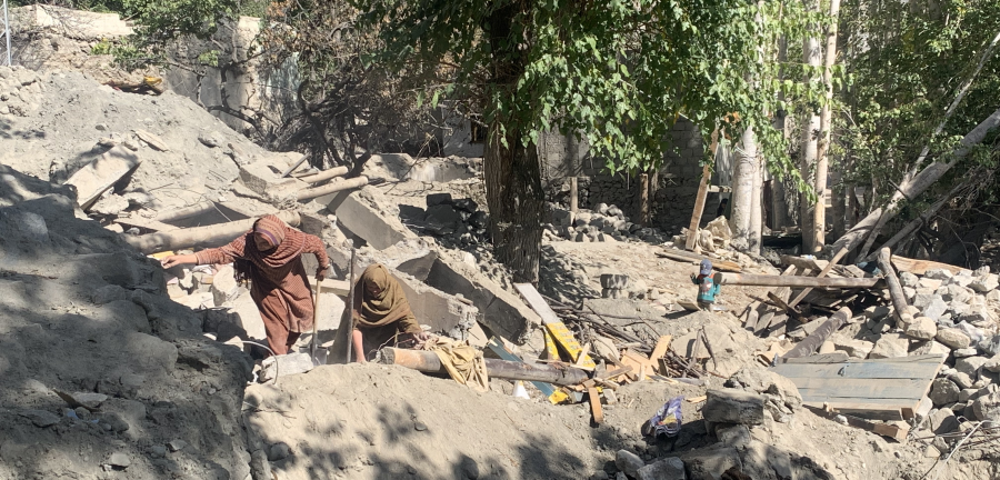 Pakistani women look for lost items among rocks.