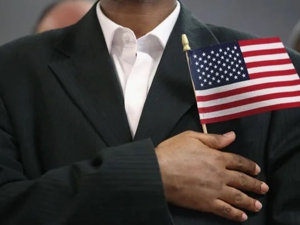 Immigrant holds flag over heart during citizenship ceremony (Getty Images)