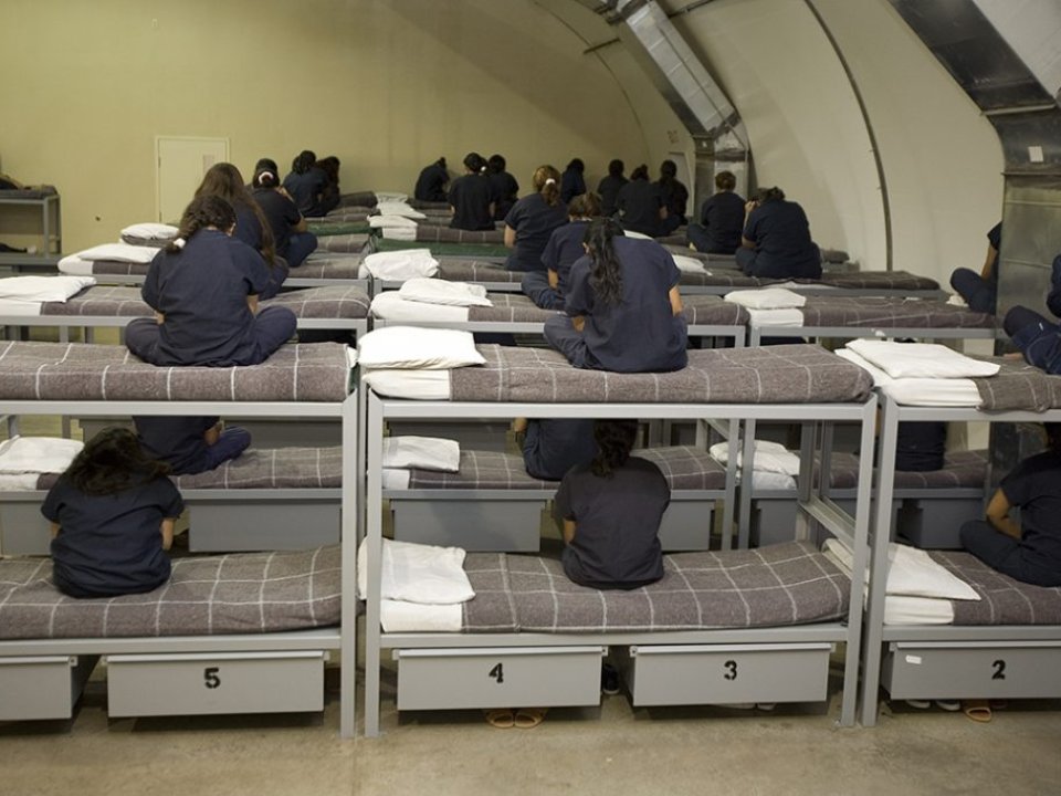 Immigrant women sit on bunk beds turned away