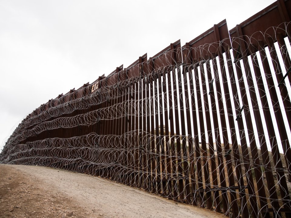 Barbed wire on a desert border wall