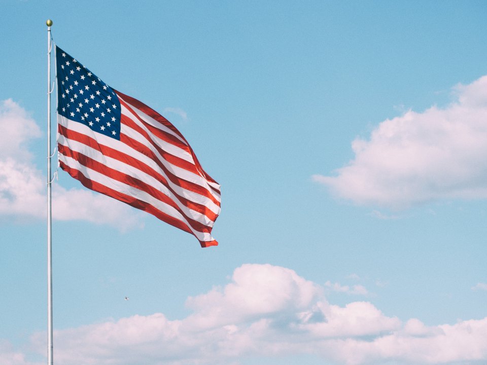 American flag flies in a blue cloudy sky