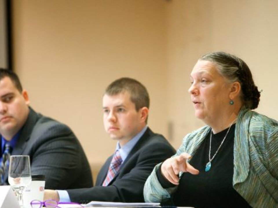 Three individuals speak at panel