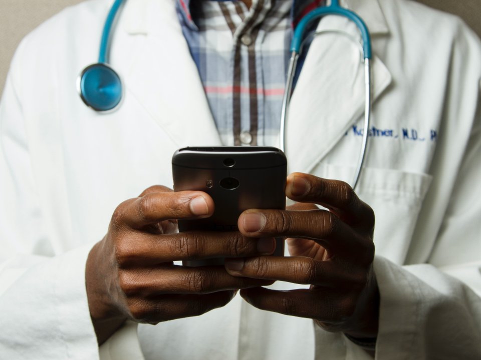 Doctor in lab coat wears stethoscope and holds smart phone