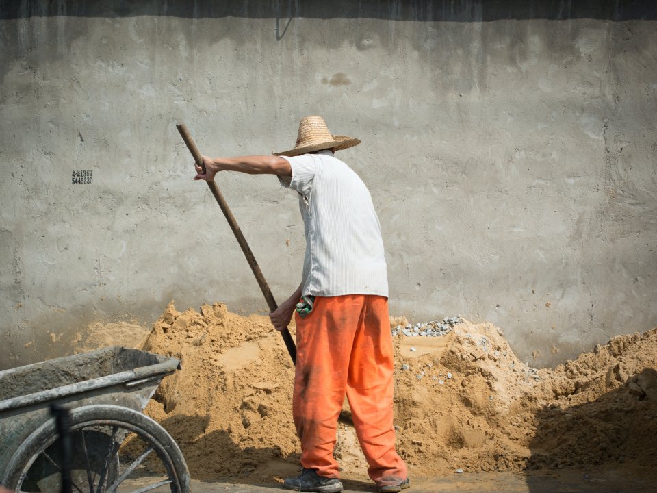 Older man shoveling sand. 