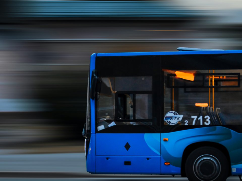 A blue bus speeds past a blurry background.