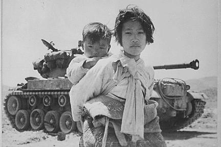 With her brother on her back, a war-weary Korean girl trudges by a stalled M-26 tank in Haengju, Korea, in 1951.