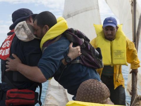 Coast guard officer hugs a migrant wearing a life vest