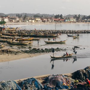 View of Cape Coast Slave Castle in Cape Coast, Ghana of small boats and homes along the shoreline. 